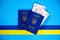 Two biometric passports of Ukrainian citizens and Ukrainian hryvnias on a blue background with a yellow and blue ribbon.