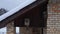 Two birdhouses attached to house facade high up near roof in winter