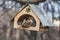 Two birds one gray and brown sparrow and one tit are in an old yellow bird and squirrel feeder house from plywood in the