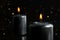 Two black candles burning at night with lights glow.