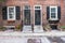 Two black front doors entrance and old-style window with shutters of a red brick house in spring.