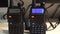 Two black handled portable walkie- talkie radio transmitter working and flashing