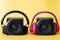 Two black one-way audio speakers and two wireless headphones with ear pads on a yellow background. Concept of a musical duet,