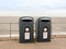 Two black recycling bins on the sea front beach for glass