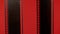 Two black vertical filmstrips on a red background in close up. Flashing light shows the scratched texture of the film.