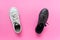 Two black and white gum rubber shoes on pink