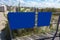 Two blank blue signs attached to the fence of a wooden boardwalk near a sandy beach