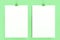 Two blank white posters with binder clip mockup on green background