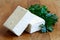 Two blocks of white tofu with fresh parsley on wooden chopping b