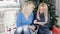 Two blond hair ladies watching into the tablet siting on the carpet near the Christmas tree