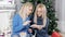 Two blond hair young ladies watching into the tablet near the Christmas tree