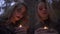 Two blonde girls with terrifying halloween makeup holding small candles in hands and looking at the camera. Gothic