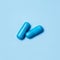 Two blue capsules. Pills for men`s health and sexual energy on an isolated background. Concept of erection, potency