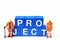 Two blue collar figurines standing next to the word `project`