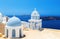 Two blue domes of the beautiful Church of Fira, Santorini in background of Caldera and the sea