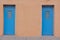 Two blue doors as entrances to a brown stucco building