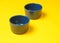 Two blue enamel bowls on yellow background.