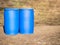 Two blue plastic barrels stand on ground