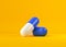 Two blue-white pill capsules over yellow background