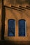 Two Blue WIndows and long shadows against warm Adobe Walls in downton Santa Fe New Mexico