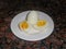 Two boiled eggs on a white plate, one in halves. showing yolk. Dark granite background. High angle