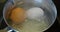 Two boiling eggs in steel pot