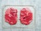 Two boneless lamb leg steaks on a plastic tray. Uncooked high quality meat product with rich taste and vivid color. On grey simple