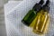 Two bottles of green natural serum and yellow organic beauty face oil for cosmetic anti age treatment skin care on towels and