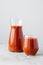 Two bottles of tomato juice containing vitamins isolated over white background. Vertical shot. Freshly squeezed smoothie. Healthy