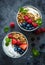 Two bowls of granola with fruits, Greek yogurt and berries top view