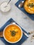 Two bowls with pumpkin soup, sauce and pumpkin seeds on a blue linen napkin. Sauce and Pumpkin Seeds. Light background. Seasonal