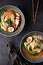 Two bowls of ramen soup with pork, shiitake and enoki mushrooms, marinated egg and vegetables