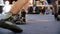 Two boxers fight in the boxing ring in boxing shoeses. Low section of male boxer standing against referee by athlete