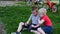 Two boy friends sit on the grass, looking at smartphone and laughing fun. Blond and dark-haired boys having fun on outdoors.