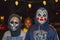 Two boys in alien and a Mexican Lucha libre wrestling masks wait for Halloween candy with little girl with big smile waiting behin