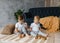 Two boys brothers plaing with wooden cube blocks on knitted carpet on the floor indoor. Knitted style in the interior: pillows,