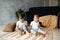 Two boys brothers plaing with wooden cube blocks on knitted carpet on the floor indoor. Knitted style in the interior: pillows,