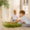 Two boys brothers plaing with wooden cube blocks on knitted grass carpet on the floor indoor. Knitted style in the interior: