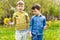 Two boys with dandelions in their hands are on the lawn in the spring