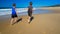 Two boys and dog running and splashing in water on the beach