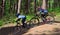 Two boys on downhill mountain bike course in woods.