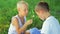 Two boys dressed in white, blowing dandelions on