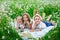 Two boys and a girl are lying in a chamomile field. Children on a picnic in nature have fun among the flowers