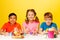 Two boys and girl paint Easter eggs at the table