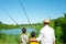 Two boys and grandfathers went fishing.  They stand on the shore of the pond and look into the distance