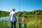 Two boys and grandfathers went fishing.  They stand on the shore of the pond and look into the distance