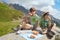 Two boys have picnic on stone in Alps