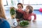 Two boys helping his mother to prepare a detox juice with blender in the kitchen at home