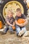 Two Boys Holding Pumpkins Talking and Sitting Against Tractor Ti