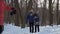 Two boys look at flying pigeon in winter park, slow motion